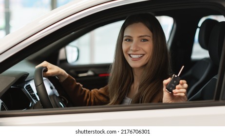 Happy Young Caucasian Woman Showing Key From Auto, Sitting Inside Car Salon, Buying New Automobile At Dealership, Banner Design. Joyful Millennial Female Purchasing Modern Vehicle At Showroom Store