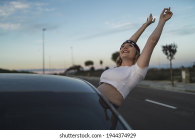 A Happy Young Caucasian Woman Wearing A Bandana With US Flag Print While Leaning Out Of Car Window