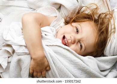 Happy Young Child Rolling In White Covers