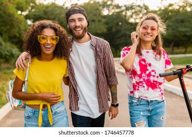 happy young company of smiling friends walking in park with electric kick scooter, man and women having fun together, colorful summer hipster fashion style, talking, smiling - Shutterstock ID 1746457778