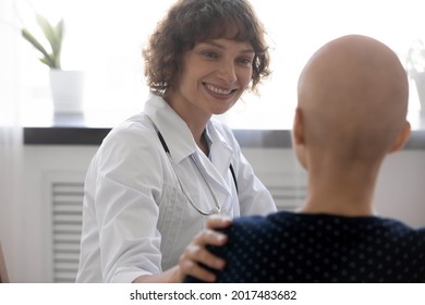 Happy Young Compassionate Kind Female Oncologist Doctor Supporting Bald After Chemotherapy Patient Woman, Telling Effective Treatment Good News Or Giving Psychological Support At Checkup Meeting.