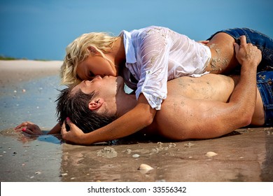 Happy young couple at the beach kissing.