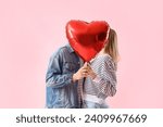 Happy young couple with beautiful heart-shaped balloon on pink background. Valentine