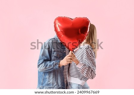 Photo of Happy young couple with beautiful heart-shaped balloon on pink background. Valentine's Day celebration