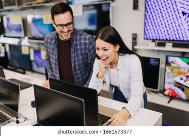 Happy Young Couple Buying Laptop In Store.