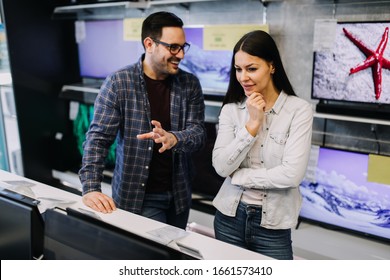 Happy Young Couple Buying Laptop In Store.