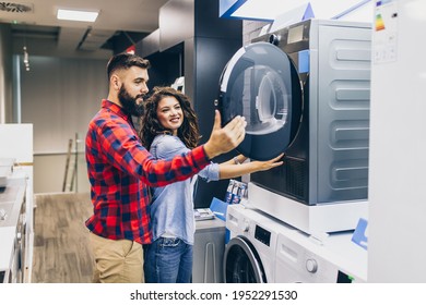 Happy Young Couple Buying Washing Machine In Appliances Store.