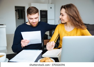 Happy young couple calculating bills at home