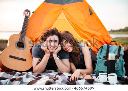 Happy young couple camping on the beach laying in the tent