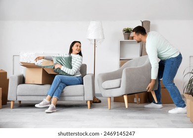 Happy young couple carrying armchair in room on moving day - Powered by Shutterstock
