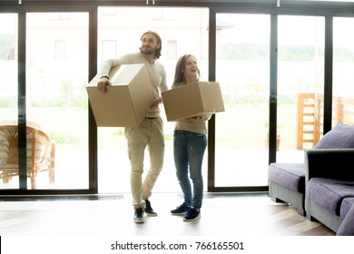 Happy Young Couple Carrying Cardboard Boxes Entering Modern Own House, Excited Married Family Property Owners Man And Woman Moving In Into New Home, Buying Real Estate, Mortgage And Relocation