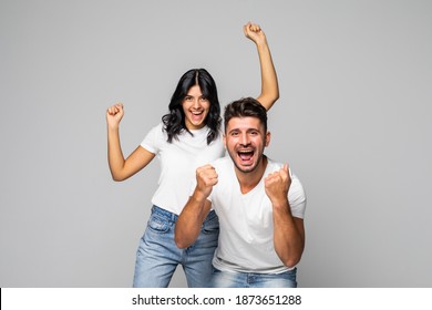 Happy Young Couple Celebrating Success With Hands Up In The Air On White Background