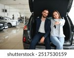 Happy young couple chooses and buying a new car for the family. Visitting the dealership.