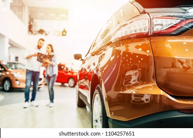 Happy Young Couple Chooses And Buying A New Car For The Family. Visitting The Dealership. 