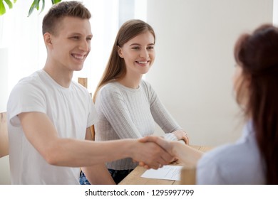 Happy Young Couple Clients Handshaking Insurer Bank Worker Advisor At Meeting, Smiling Hr Recruiters And Applicant Shaking Hands Greeting At Job Interview Hiring Making First Impression, Recruiting