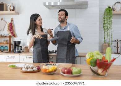 Happy young couple cooking together in the kitchen counter at home - Powered by Shutterstock