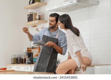 Happy young couple cooking together in the kitchen counter at home - Powered by Shutterstock