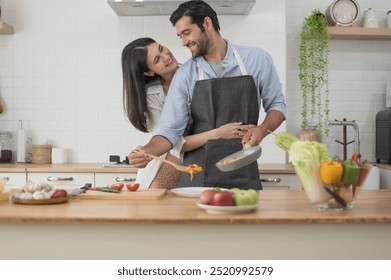 Happy young couple cooking together in the kitchen counter at home - Powered by Shutterstock