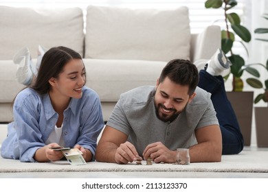 Happy Young Couple Counting Money On Floor At Home