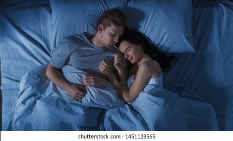 Happy Young Couple Cuddling Together in the Bed Sleeping at Night. Beautiful Girl and Handsome Boy Sleeping Together, Sweetly Embracing Each other. Top Down Shot. - Powered by Shutterstock