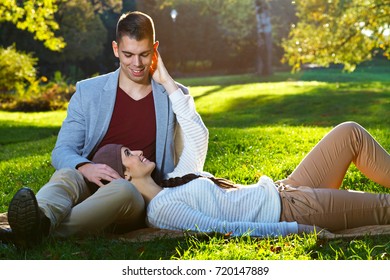 Happy Young Couple Cuddling While Laying On The Grass