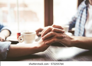 Happy young couple is drinking coffee, talking and smiling while sitting at the cafe - Powered by Shutterstock