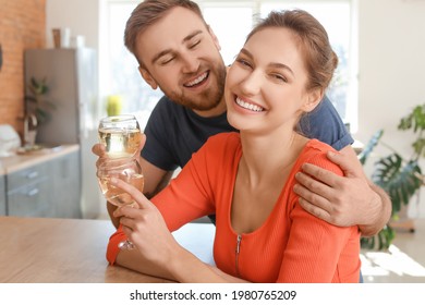 Happy young couple drinking wine in kitchen