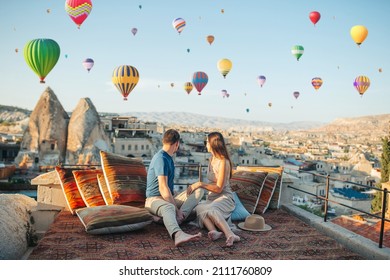 Happy young couple during sunrise watching hot air balloons in Cappadocia, Turkey - Shutterstock ID 2111760809