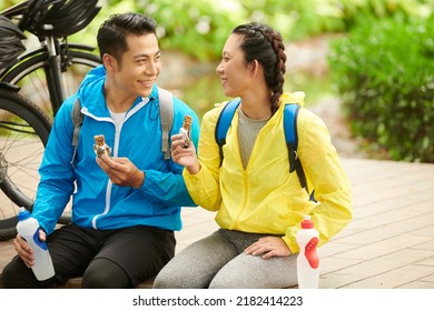 Happy Young Couple Eating Energy Bars After Bicycle Ride To Get More Energy