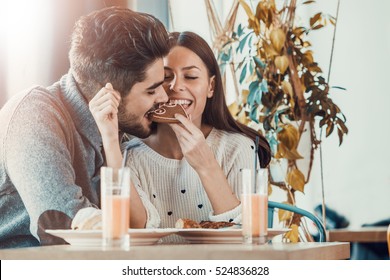 Happy young couple eating pastries in a pastry shop.