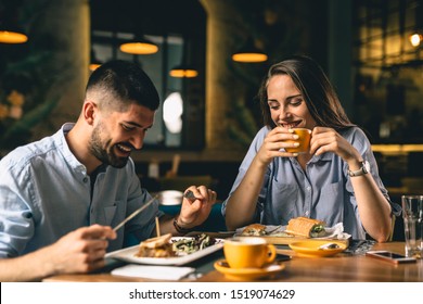 Happy Young Couple Eating In Restaurant