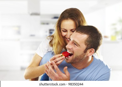 happy young couple eating strawberries together