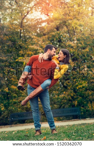 Happy young couple enjoying city park. Young man carrying girlfriend piggyback