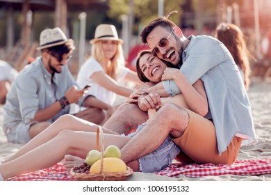 Happy young couple enjoying picnic on the beach and have good time on summer vacation. - Powered by Shutterstock