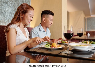 Happy Young Couple Enjoying Tasty Dinner In Fancy Restaurant