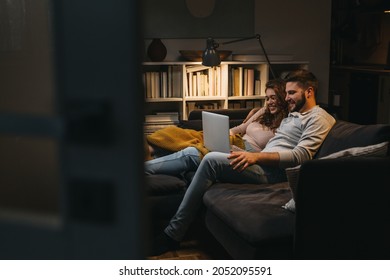 Happy Young Couple Enjoying Time At Home Using Laptop Computer