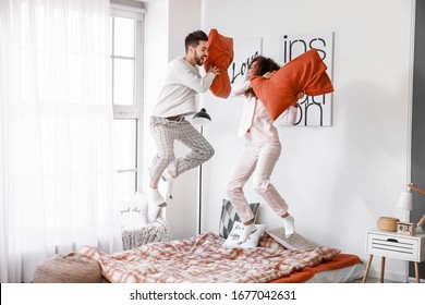 Happy young couple fighting on pillows in bedroom - Powered by Shutterstock