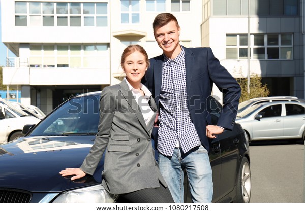Happy\
young couple in formal clothes near car\
outdoors