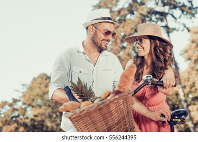 Happy Young Couple Going For A Bike Ride On A Sunny Day In The Park.