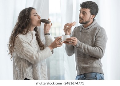 Happy young couple having breakfast at home looking out the window. It's a nice day to reflect while having a coffee. Breakfast is the most important meal in the diet. Balanced diet, renewed energy. - Powered by Shutterstock