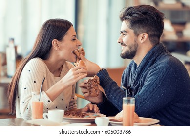 Happy young couple having breakfast in cafe,enjoying together.