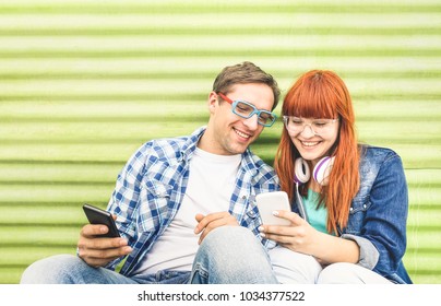 Happy young couple having fun with mobile smart phone at vintage grunge location - Friendship concept with hipster best friends connecting with new technologies - Millennial generation dating online