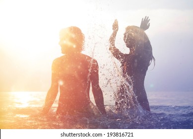 Happy Young Couple Having Fun, Man And Woman In The Sea On The Beach. Vintage Retro Style With Soft Focus And Sun Flare