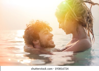 Happy Young Couple Having Fun, Man And Woman In The Sea On The Beach. Vintage Retro Style With Soft Focus And Sun Flare