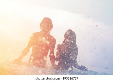 Happy Young Couple Having Fun, Man And Woman In The Sea On The Beach. Vintage Retro Style With Soft Focus And Sun Flare