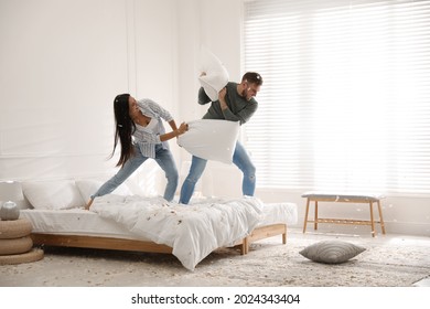 Happy young couple having fun pillow fight in bedroom - Shutterstock ID 2024343404