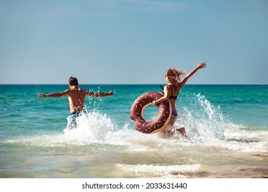 Happy young couple are having fun with inflatable donut at sea beach. Tropical vacations concept - Powered by Shutterstock