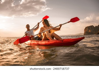 Happy young couple is having fun and walking on kayak at sunset sea. Krabi province, Phranang beach, Thailand