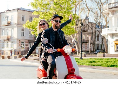 Happy Young Couple Having Fun Riding The Scooter During Sunset Or Sunrise. Couple On Motorbike In City