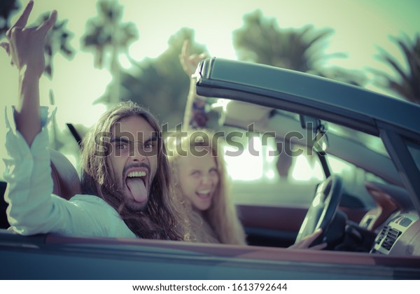 Happy young couple\
having fun inside convertible sport car. Couple listening to rock\
music. Vacation, journey and relationship concept. Focus on man\
face - Image
